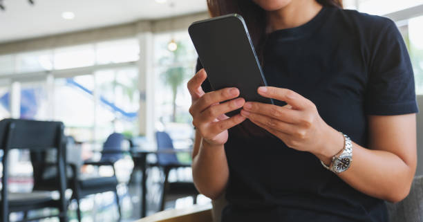 istock Closeup image of a woman holding and using mobile phone in cafe 2185683372