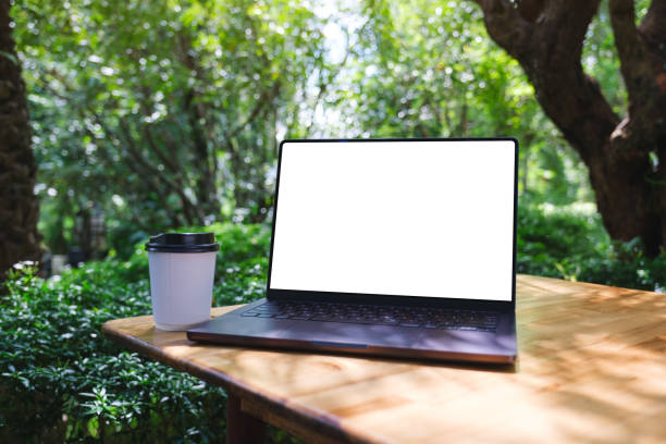 istock Mockup image of a laptop computer with blank white desktop screen and coffee cup on the table in the outdoors 2185683394