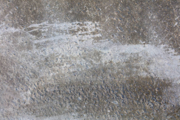 A grey concrete wall with a few cracks and a few spots. The wall is rough and uneven