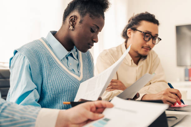 istock Diverse young professionals reading documents together during collaborative meeting in bright office space 2185686818
