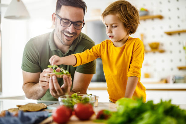 Happy father and son making a sandwich in the kitchen.