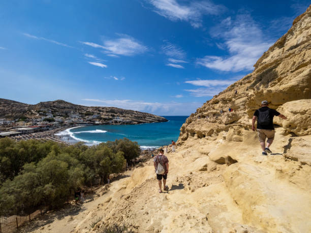 Matala, Greece - September 16 2024: Caves at Matala beach. The artificial caves in the cliff of the Matala bay were created in the Neolithic Age.