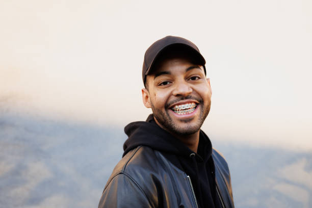 istock Smiling african american man in baseball cap looking at camera near wall with shadow 2185695052