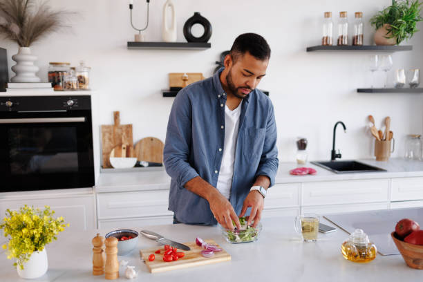 istock African american man cooking salad in kitchen at home 2185695565