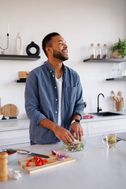 istock Cheerful african american man cooking fresh salad in kitchen 2185695620