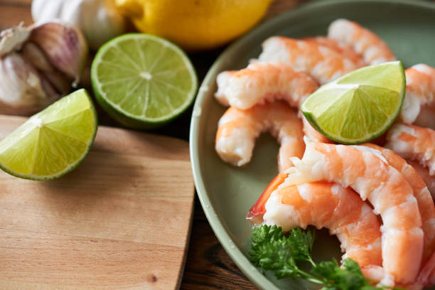 istock Raw shrimp with lime and parsley on wooden table, closeup 2185697435