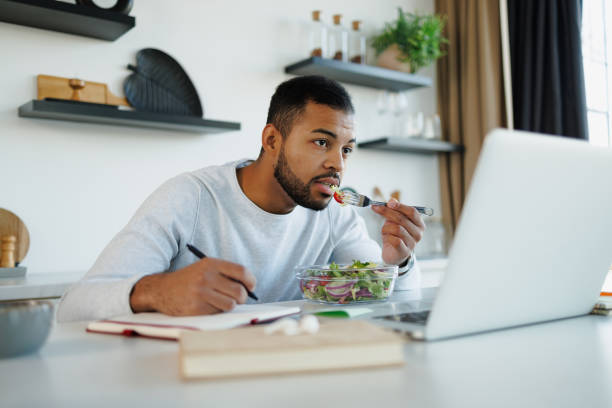 istock African american freelancer eating fresh salad while working in kitchen 2185697490