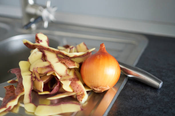 Peel potatoes and onions in the kitchen sink. Peeled vegetables.