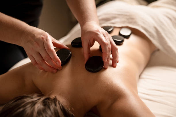 istock A massage therapist places hot stones on a client's back during a stone therapy session. Hot stone massage concept 2185702265