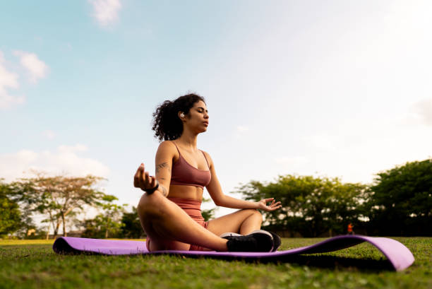 istock Young woman meditating in a public park 2185702543