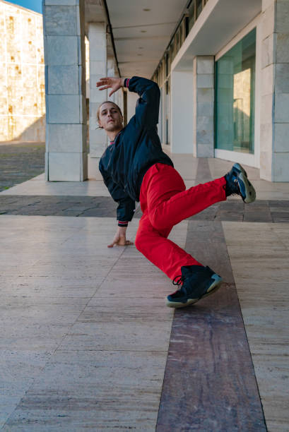 istock A man in black jacket and red pants is doing a breakdancing exercise on a sidewalk. Space to write 2185703199