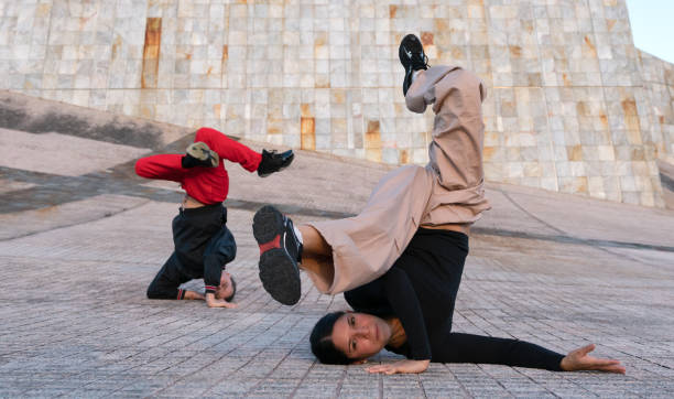 istock A woman striking a breakdance pose on the floor. A man strikes another pose behind her 2185703217