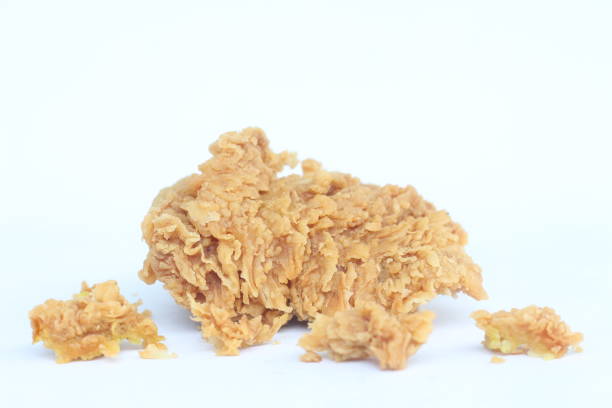 A piece of fried chicken is sitting on a white background. The chicken is golden brown and crispy, with a slightly charred flavor. Concept of indulgence and satisfaction