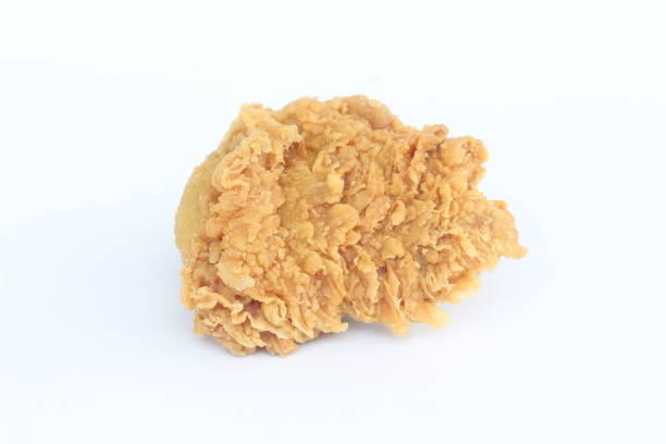 A piece of fried chicken is sitting on a white background. The chicken is golden brown and crispy, with a slightly charred flavor. Concept of indulgence and satisfaction
