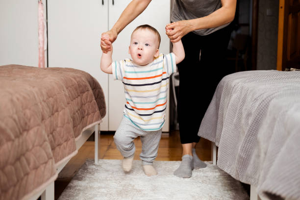 istock happy little baby learning to walk with mother help at home 2185707428