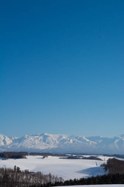 Field and snowy mountains on a clear winter day Mt. Tokachidake