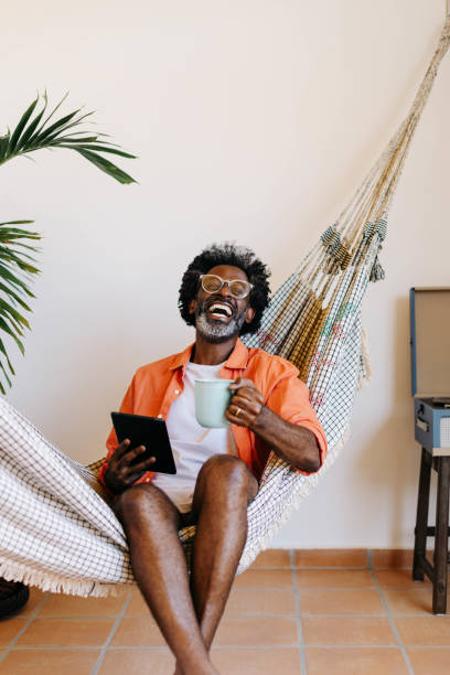 istock Relaxed man enjoying coffee and technology in a hammock 2185708467
