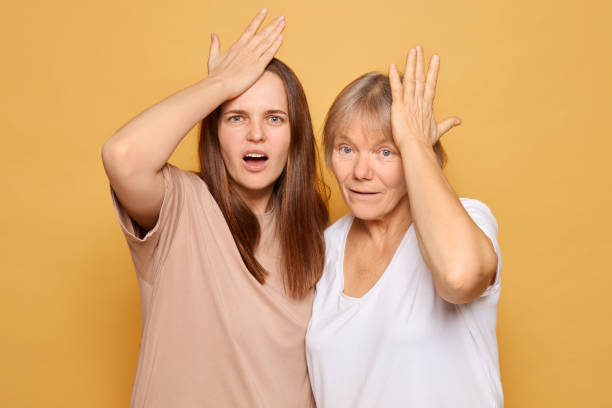 istock Two women displaying surprise and disbelief against a vibrant yellow background while touching their foreheads in a playful manner, showcasing their expressions during a lighthearted moment 2185711194