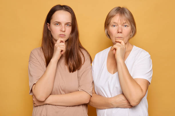 istock Two women posing thoughtfully against a solid yellow background, showcasing their contemplative expressions and connection in a moment of reflection 2185711240