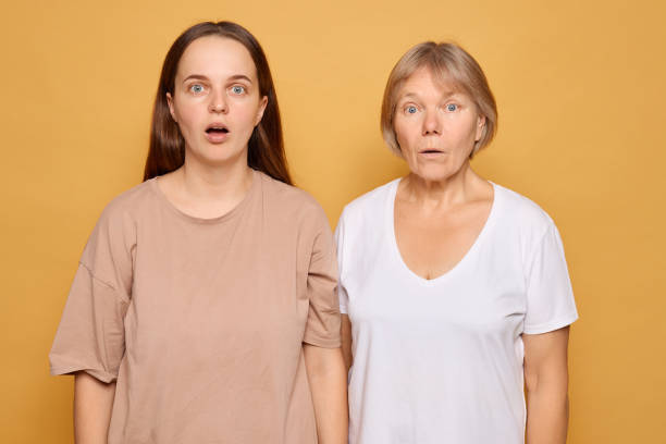istock Two women with surprised expressions stand side by side against a bright yellow background in a studio setting, showcasing a moment of shared astonishment 2185711241