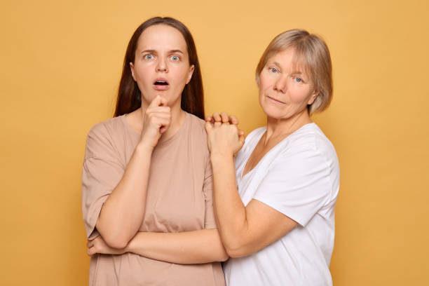 istock Two women expressing surprise and concern with a playful yet serious demeanor against a bright yellow background in a studio setting 2185711253
