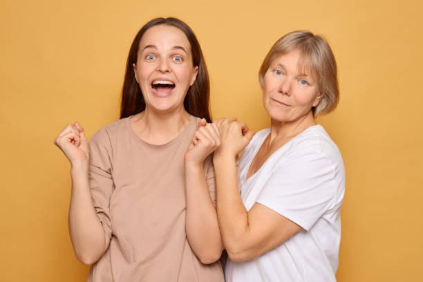 istock Two women celebrating joyfully together against a bright yellow backdrop, expressing happiness and connection, showcasing a moment of shared excitement 2185711255