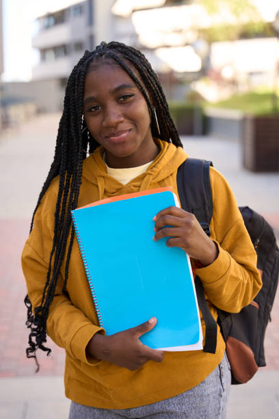 istock Smiling student holding books and walking on campus 2185716388