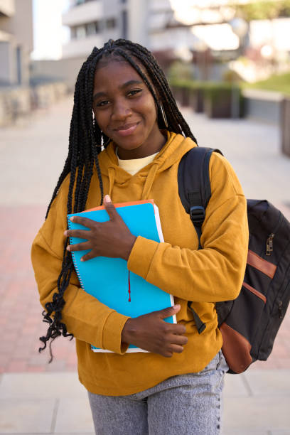 istock Smiling student holding books and walking on campus 2185716394
