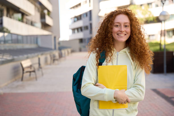 istock Smiling student holding books at university campus 2185716407