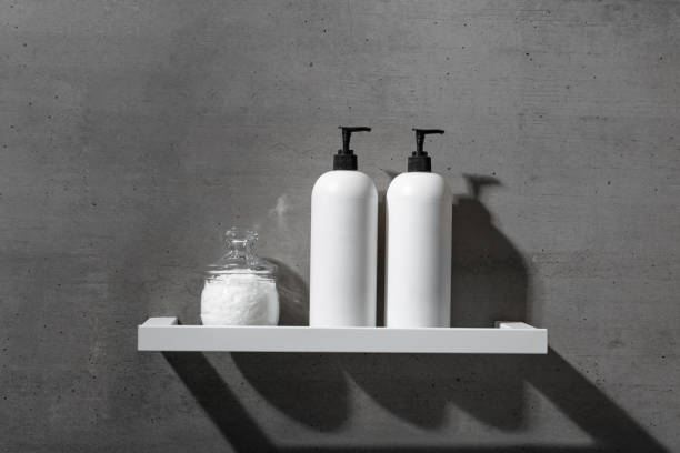 istock White bottles with shampoo, conditioner and bath salt on white shelf on gray concrete background. Aesthetic view beauty products in modern minimal bathroom neutral color. Side view, copy space 2185722503