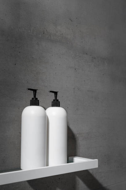 istock Two minimalist white bottles with black pump caps on white shelf against texture gray concrete background. Neutral tones minimalist interior design bathroom. Skincare, body care, beauty products 2185722513