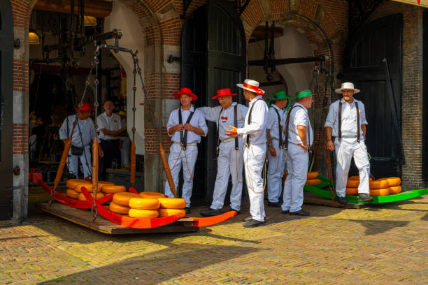 Alkmaar, The Netherlands - July 19, 2024: Carriers walking with cheese at the touristic cheese market in Alkmaar, Netherlands, with tourists in the background