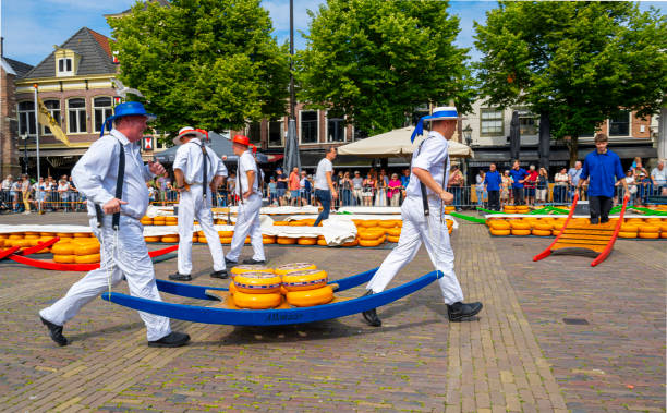 Alkmaar, The Netherlands - July 19, 2024: Carriers walking with cheese at the touristic cheese market in Alkmaar, Netherlands, with tourists in the background