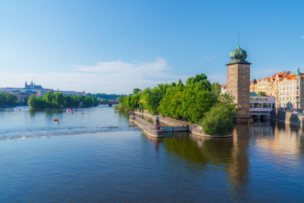 A tranquil scene of the Vltava River in Prague, Czech Republic, with boats gliding past the historic buildings lining the shore