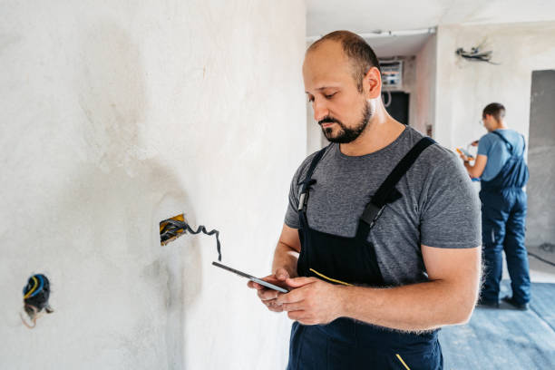 istock Electrician Planning The Renovations On A Digital Tablet In An Empty Apartment 2185723404