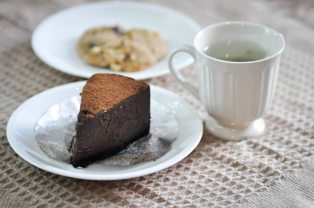 The woman enjoying her slice of cake and a cup of tea, close up.