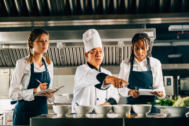 istock In a restaurant kitchen a senior Asian chef educates multiracial students. Emphasizing teamwork learning and note-taking in this professional setting. Food Edocation 2185725218