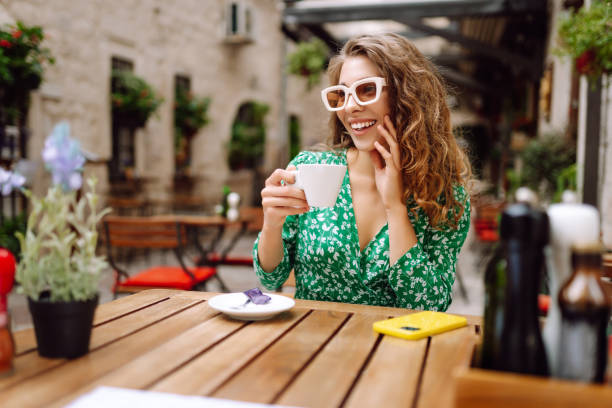 istock Happy young woman drinking tea, coffee while sitting in a cafe. 2185726899