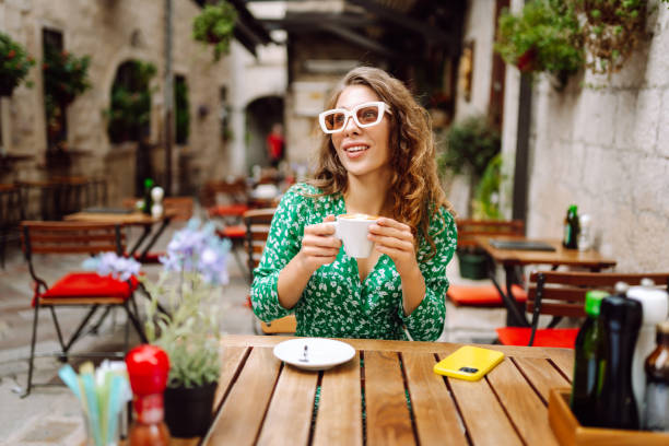 istock Happy young woman drinking tea, coffee while sitting in a cafe. 2185726913