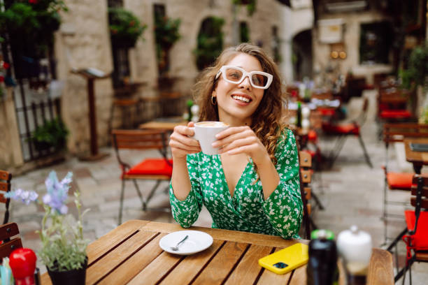istock Happy young woman drinking tea, coffee while sitting in a cafe. 2185726918