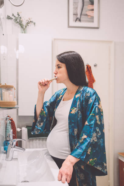 istock At home - young woman brushing her teeth 2185727065