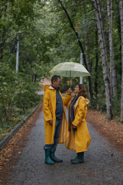 istock Happy embraced senior couple walking with umbrella at forest 2185729078