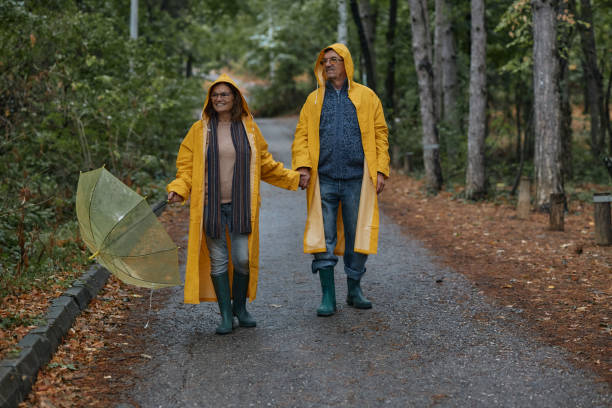 istock Happy embraced senior couple walking with umbrella at forest 2185729105