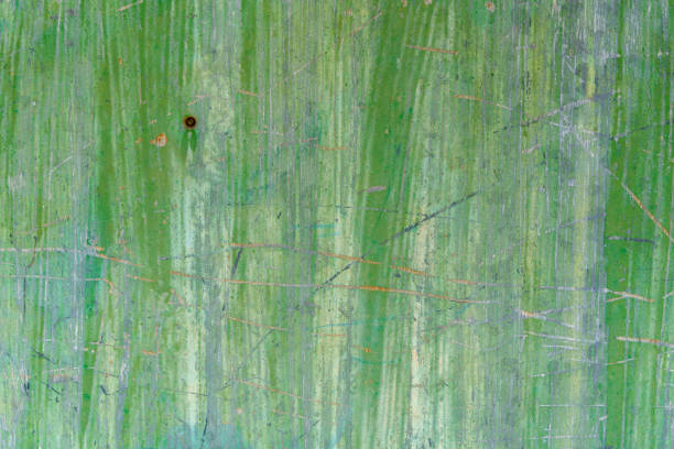A close-up of a green textured wall showing scratches and faint streaks of wear. The surface features a mix of vibrant green tones, with subtle discoloration and markings, creating a rustic and aged appearance.