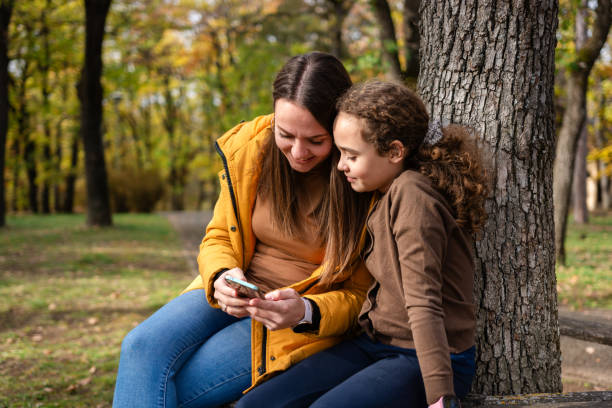 istock Mother and daughter use mobile phone outside 2185733928