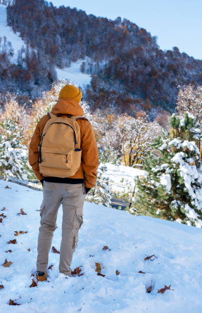 istock rear view of a man in a red jacket and hat with a yellow backpack admiring a beautiful mountain view with an autumn-winter forest landscape Hiking and tourism 2185734372