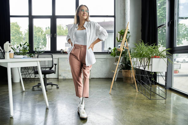 istock Young woman with prosthetic leg confidently poses in bright office environment 2185747080