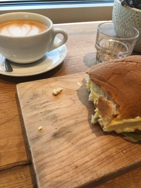 istock Coffee latte and egg breakfast sandwich on wooden table in modern cafe 2185749238