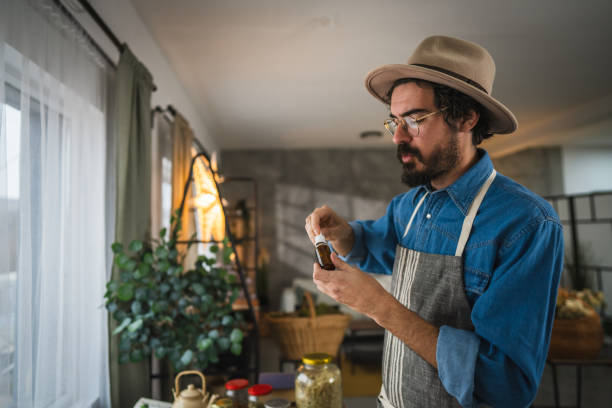 side view of man herbalist hold bottle with natural oils in workshop