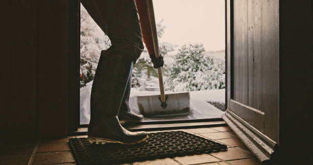 Senior woman clearing snow from her front door